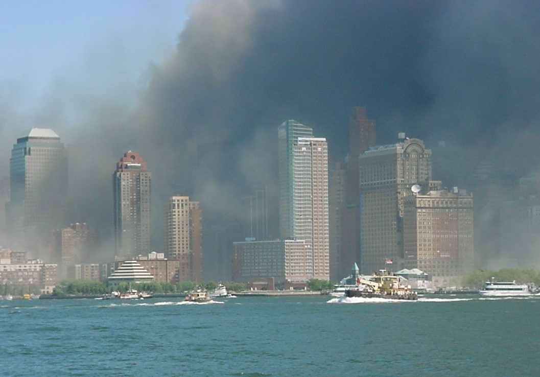 high rise smoke-filled skyline with boats and water in foreground
